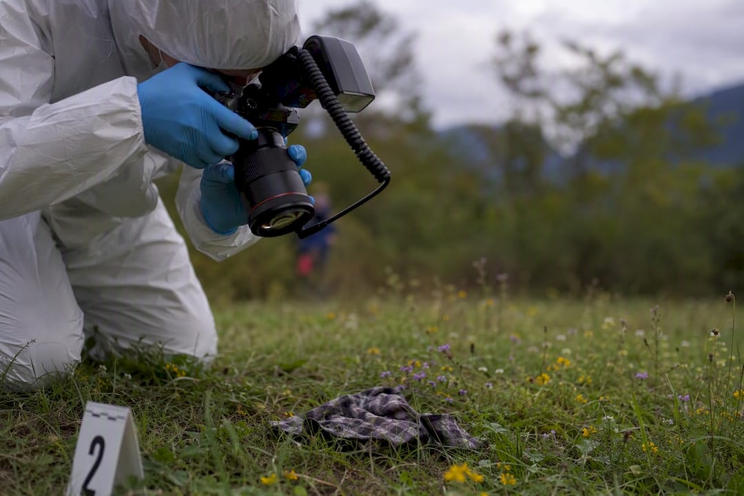 Forensic investigator photographing evidence outdoors