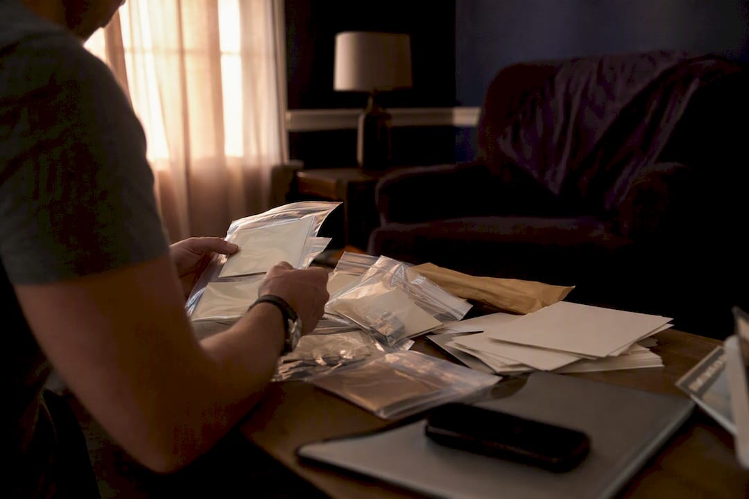 Hands sorting evidence bags on desk